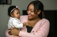2022年1月18日，在威斯康星州沃瓦托萨，Khola Cooksey抱着她的女儿Nyla。这位同侪咨询师将她的时间分配给密尔沃基的非裔美国母乳喂养网络和密尔沃基的妇女、婴儿和儿童项目。她认为这两家公司都对家庭友好，帮助她支持自己服务的母亲。安琪拉主要/ WPR