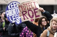 2022年5月3日，威斯康星州麦迪逊，支持堕胎权利的抗议者在威斯康星州国会大厦前举着标语，听演讲者讲话。如果美国最高法院推翻具有里程碑意义的罗伊诉韦德案判决，威斯康星州的堕胎将面临不确定的法律前景。(安吉拉·梅杰/ WPR)