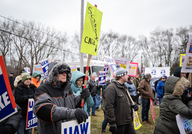 2022年12月17日，罢工工人和支持者在威斯康星州拉辛的美国汽车工人联合会大厅举行的集会上举着标语。安琪拉主要/ WPR