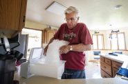2021年6月1日星期二，在威斯康星州法兰奇岛的家中，Dale Wetterling将一袋冰倒进一个盒子里，然后将其放入冰箱。他和妻子玛丽使用Kwik Trip的冰，因为他们的水受到PFAS污染。安琪拉主要/ WPR